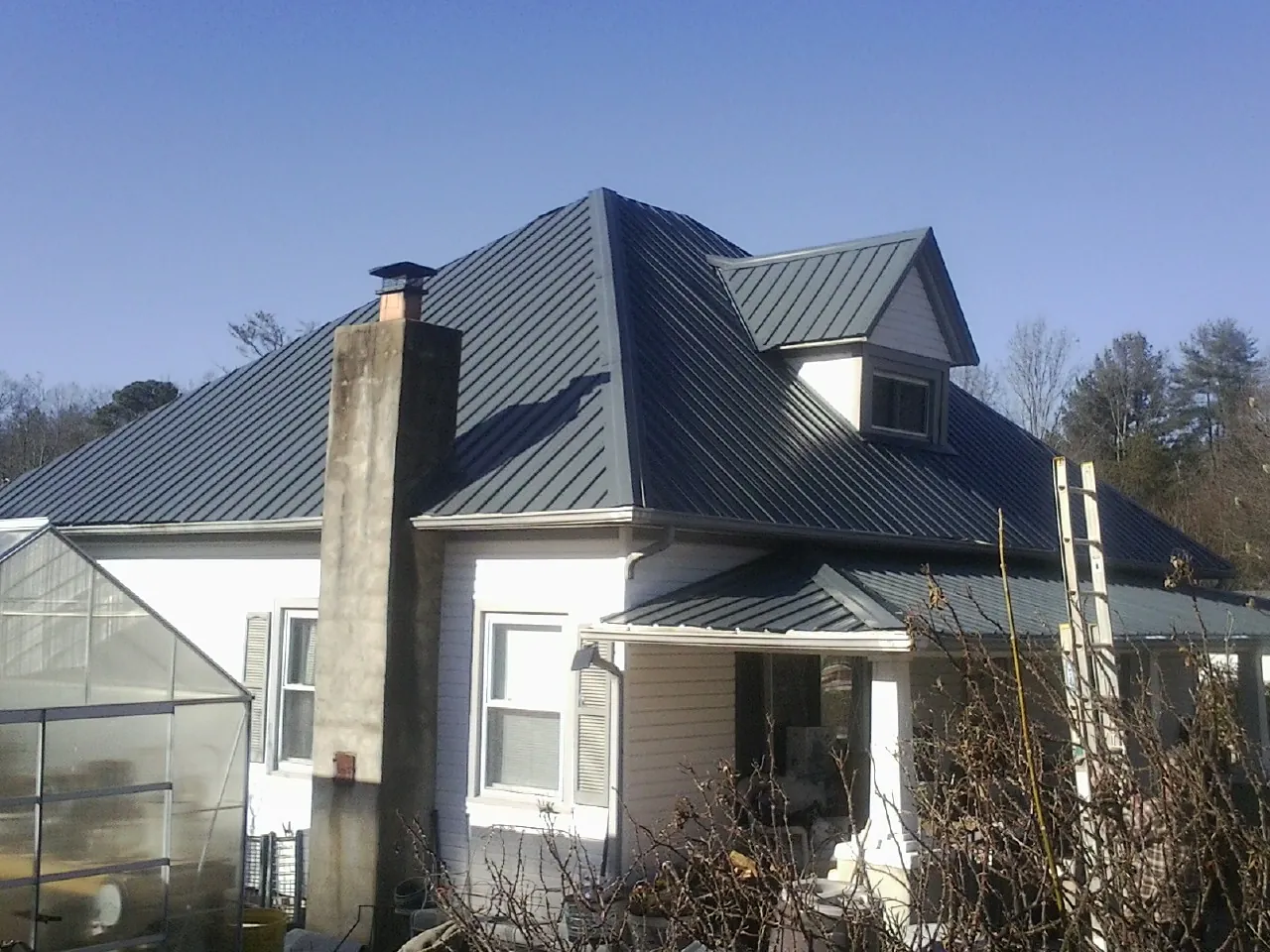 Dark blue standing seam metal roof on a white farmhouse with dormer — Slate & Tile Roof Repair by Roofing Brothers in Verdon
