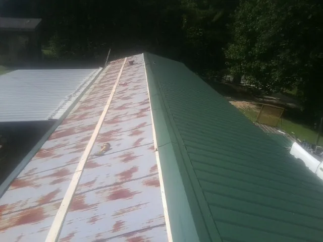 Old rusted panels beside newly installed green metal roofing — Wind Damage Roof Repair by Roofing Brothers in Verdon