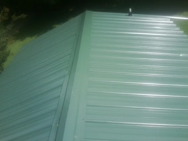 New green metal panels meeting at the ridge of a roof — Flat Roof Repair work by our crew in Verdon