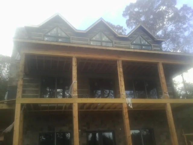 Dormers and porch framing on a large log home under construction — Roof Coating work by our crew in Verdon