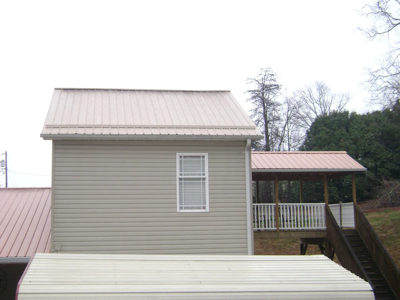 Tan metal roofs on a two story addition and attached porch, from a Roof Replacement job in Verdon